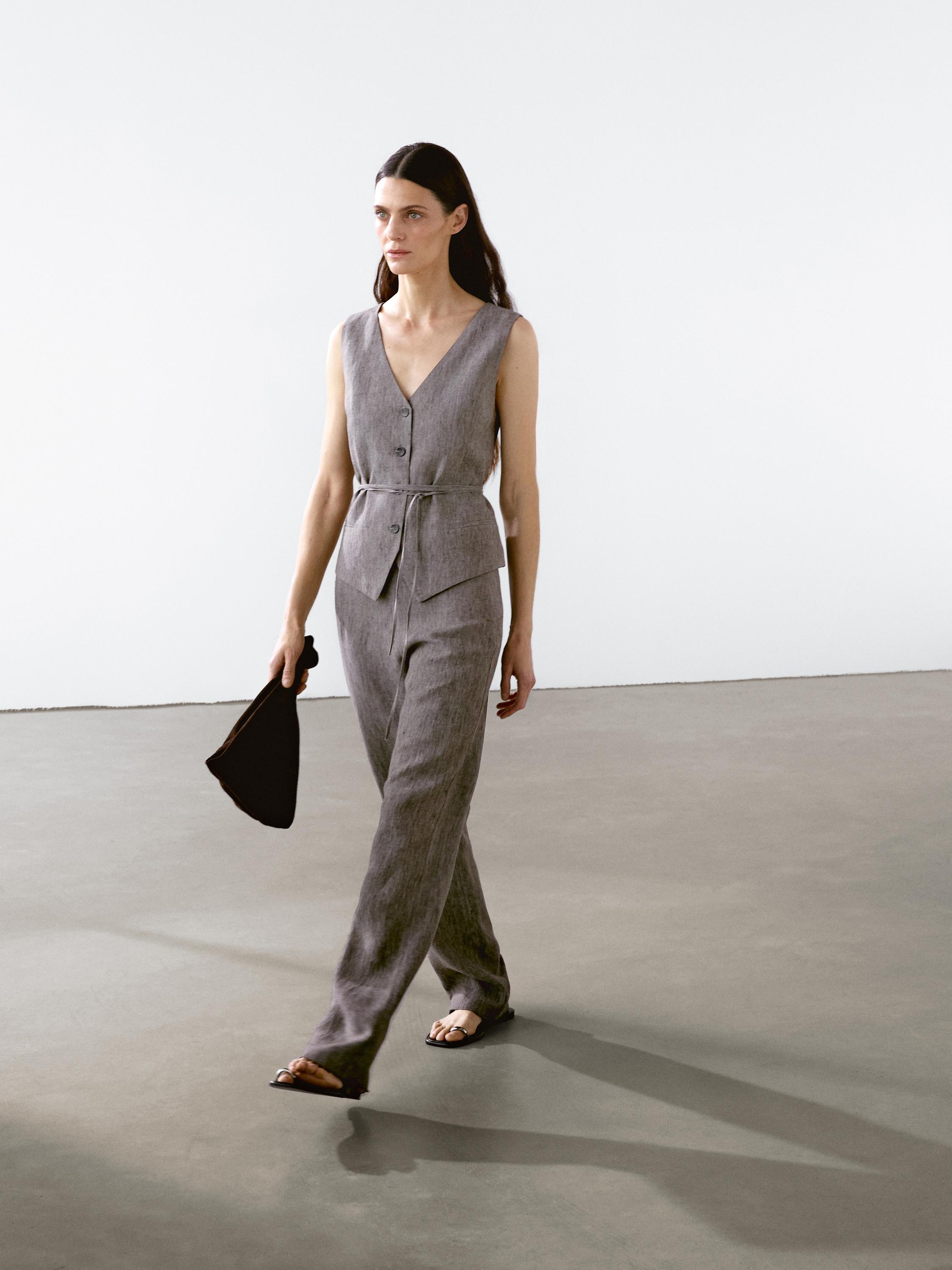 طقم بنطلون و صدرية رمادي، بدون أكمام، مع حزام و أزرار أمامية، جيوب أمامية ظاهرة.