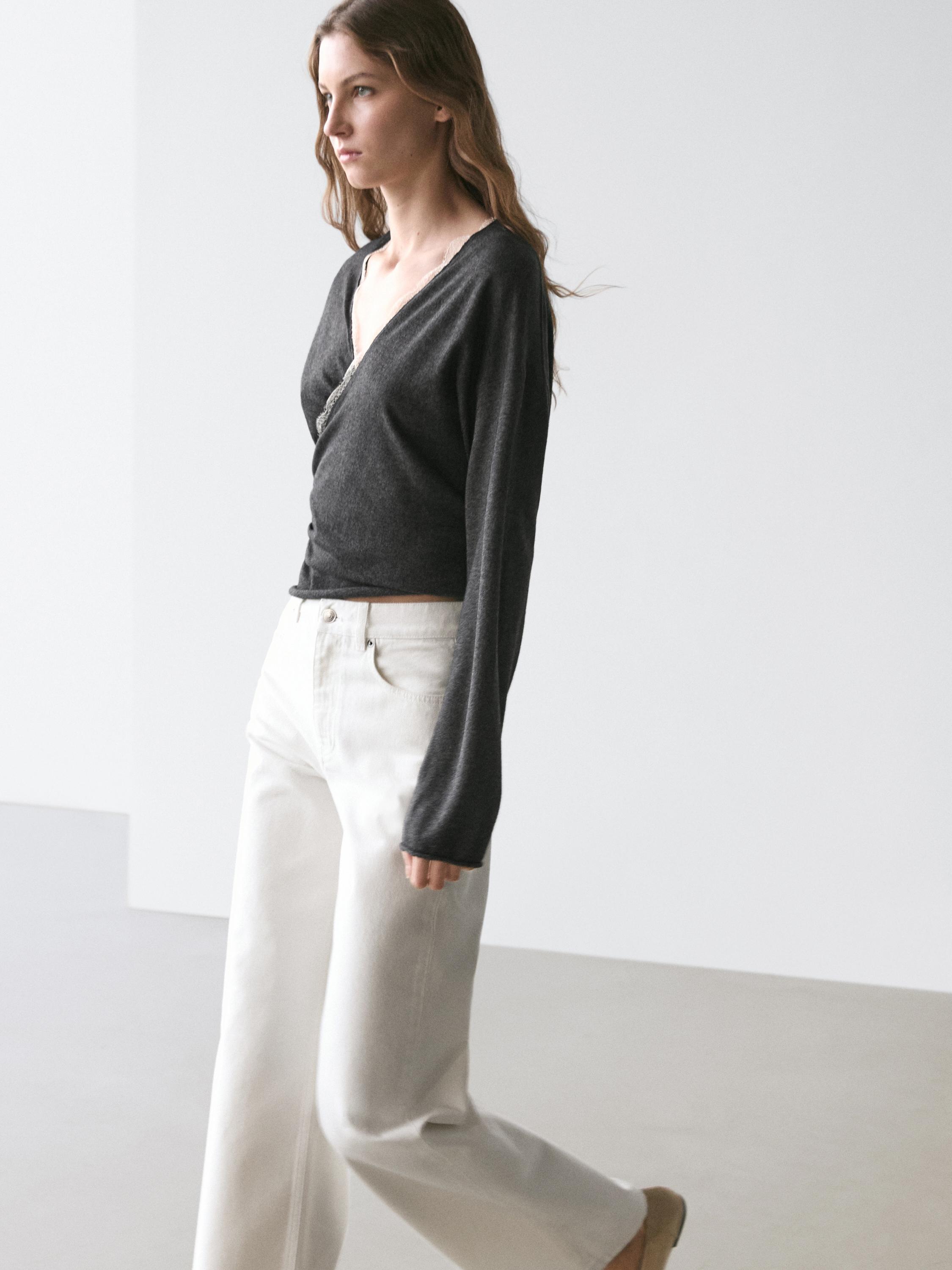 طقم كارديجان رمادي فحمي متقاطع مع تفاصيل دانتيل وبنطلون أبيض واسع الساق.