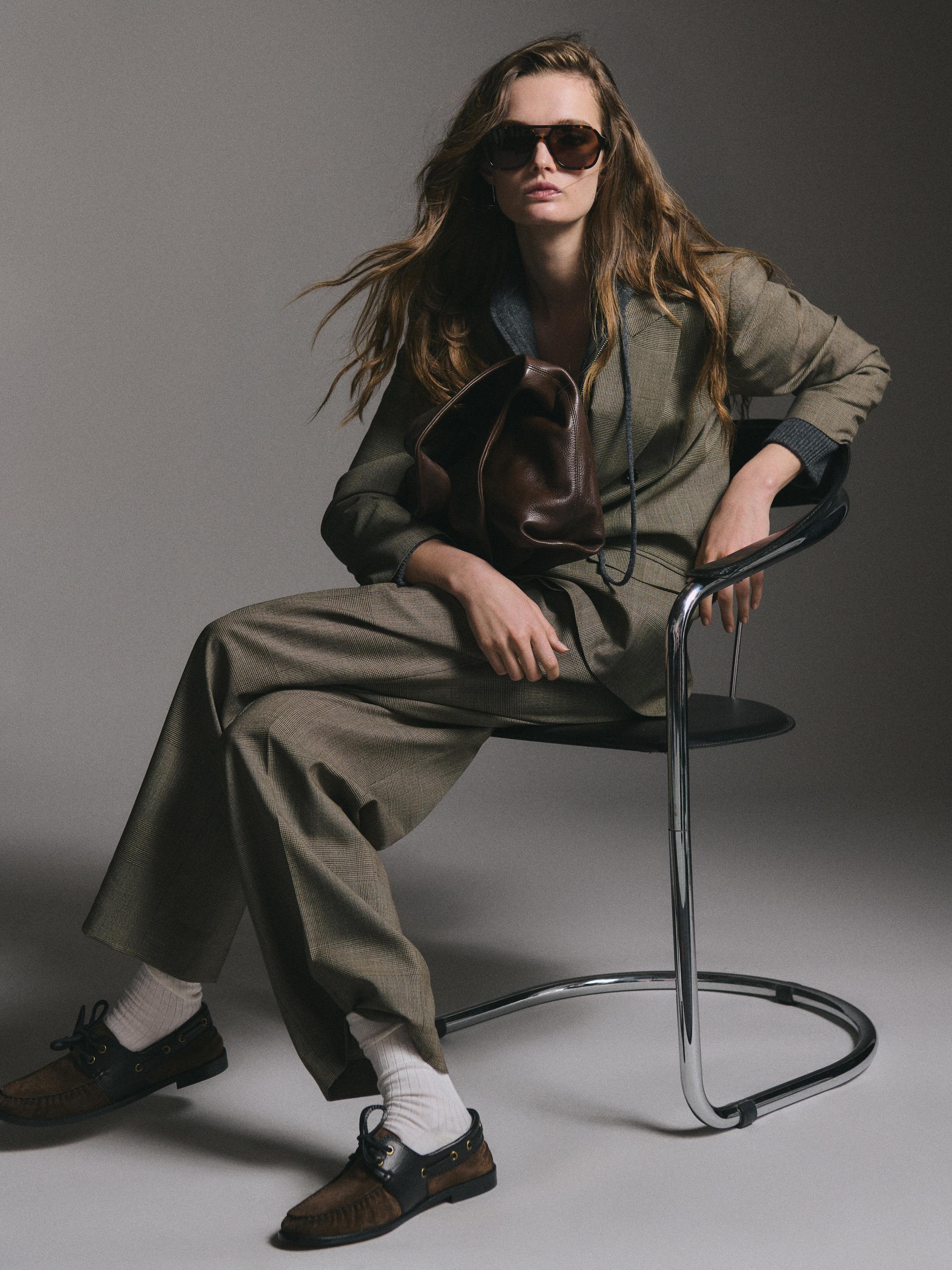 Кафяв костюм с яке с ревер и широки панталони. Кафяви обувки с бели чорапи. Кафява чанта.