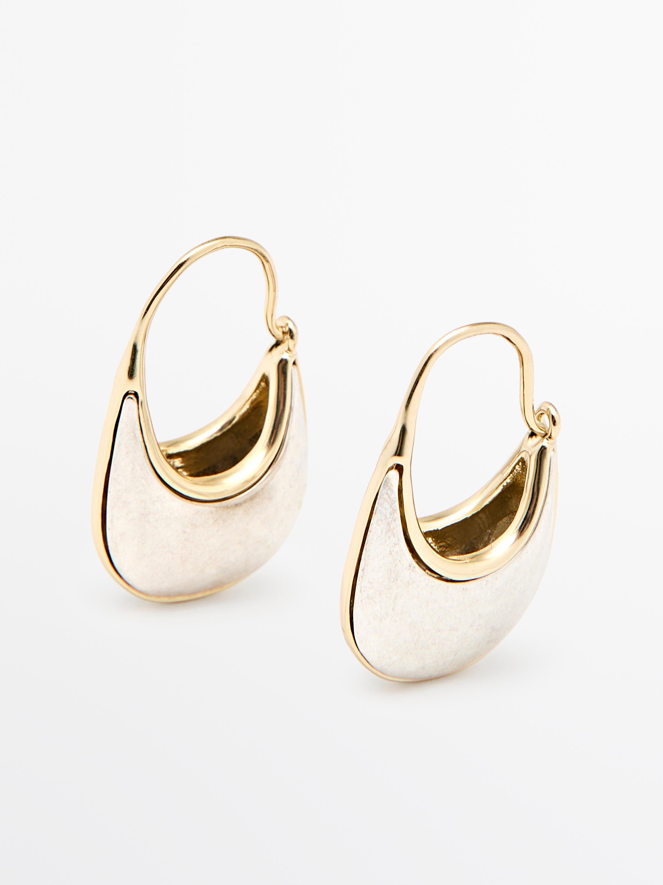Silver and gold-colored hoop earrings with a curved design and hook closure.