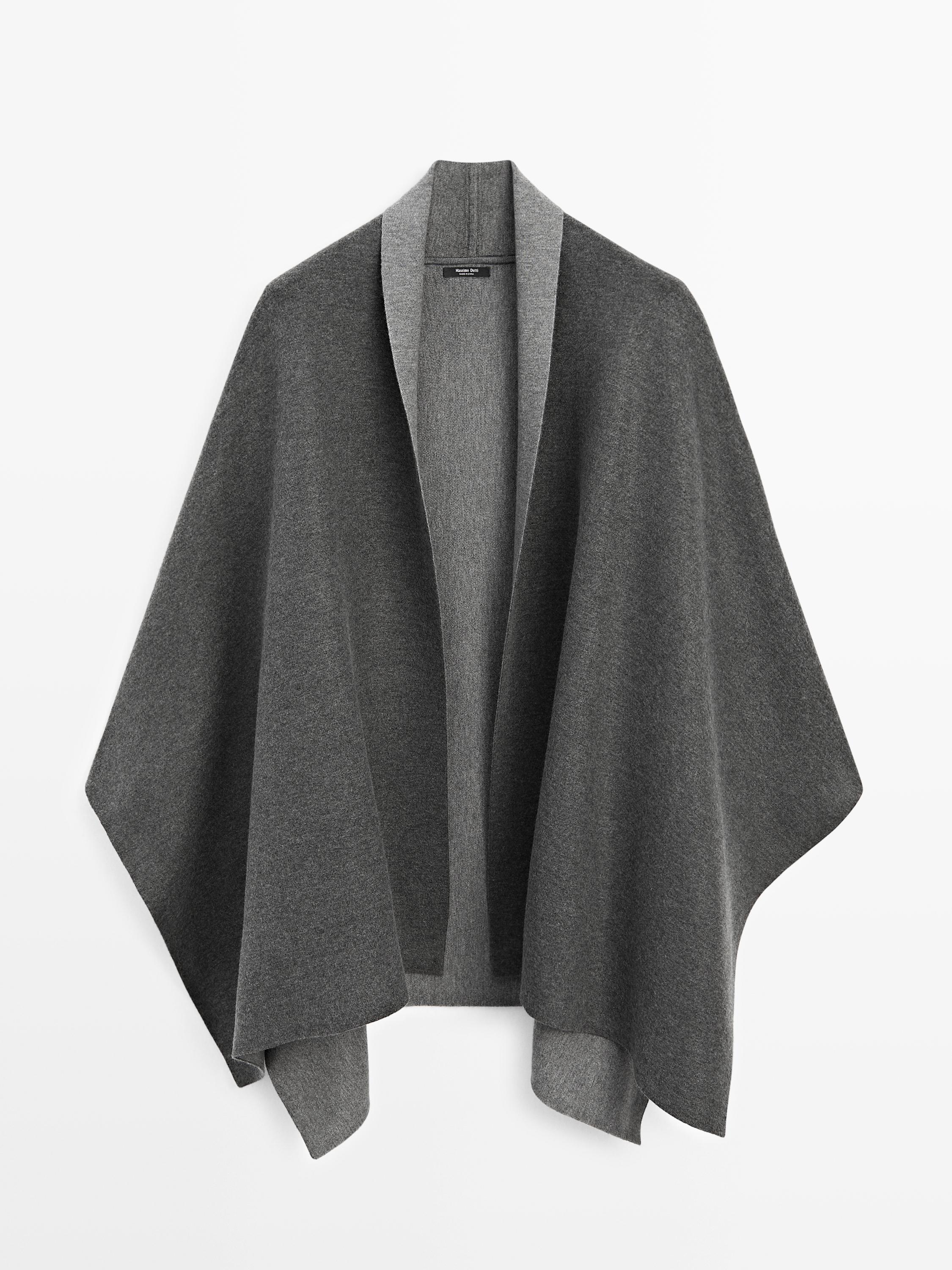 Vue de face d'une cape grise avec un motif ouvert et des bords contrastants.