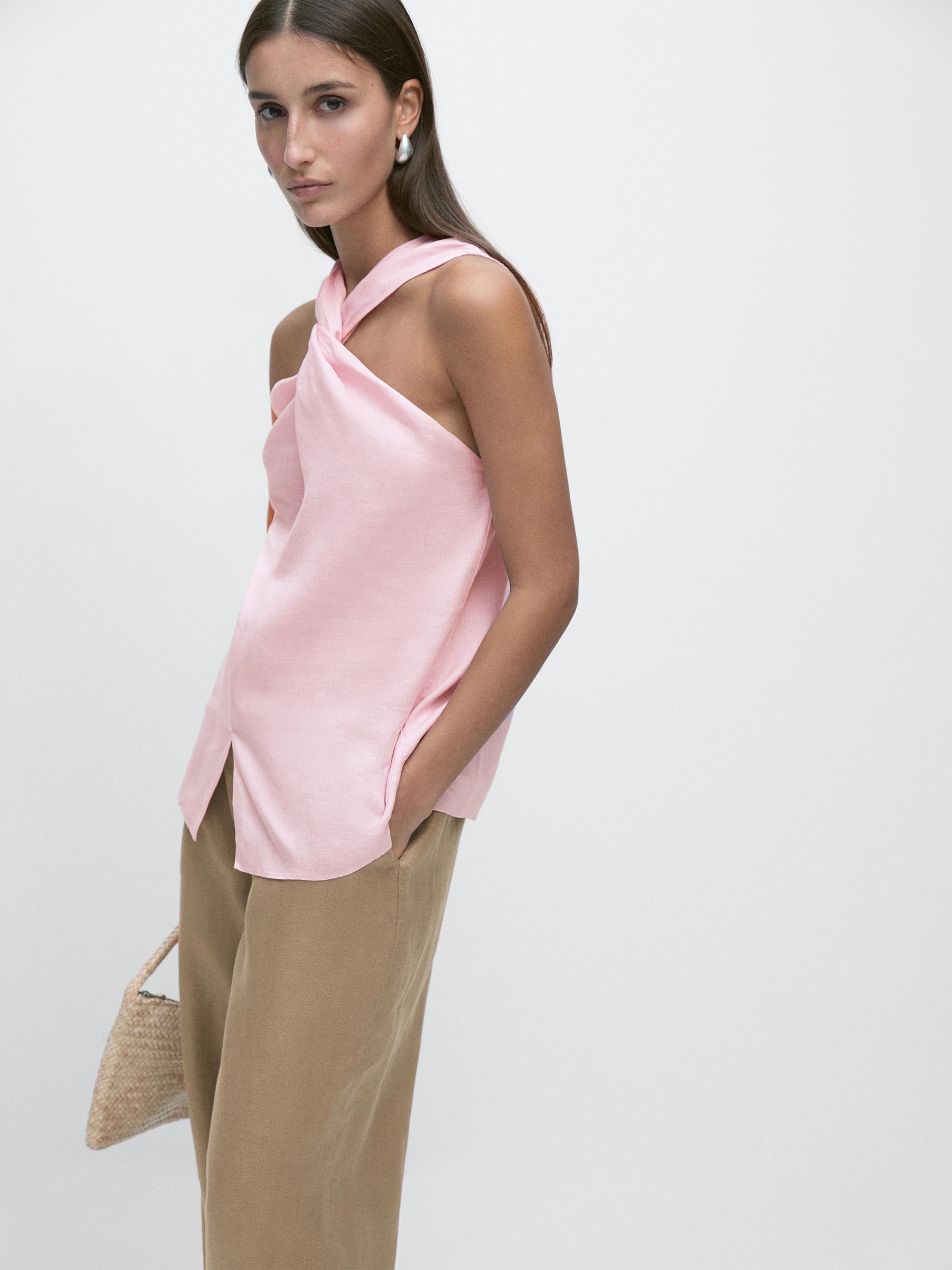 Conjunto de top rosa cruzado sin mangas y pantalones beige rectos.