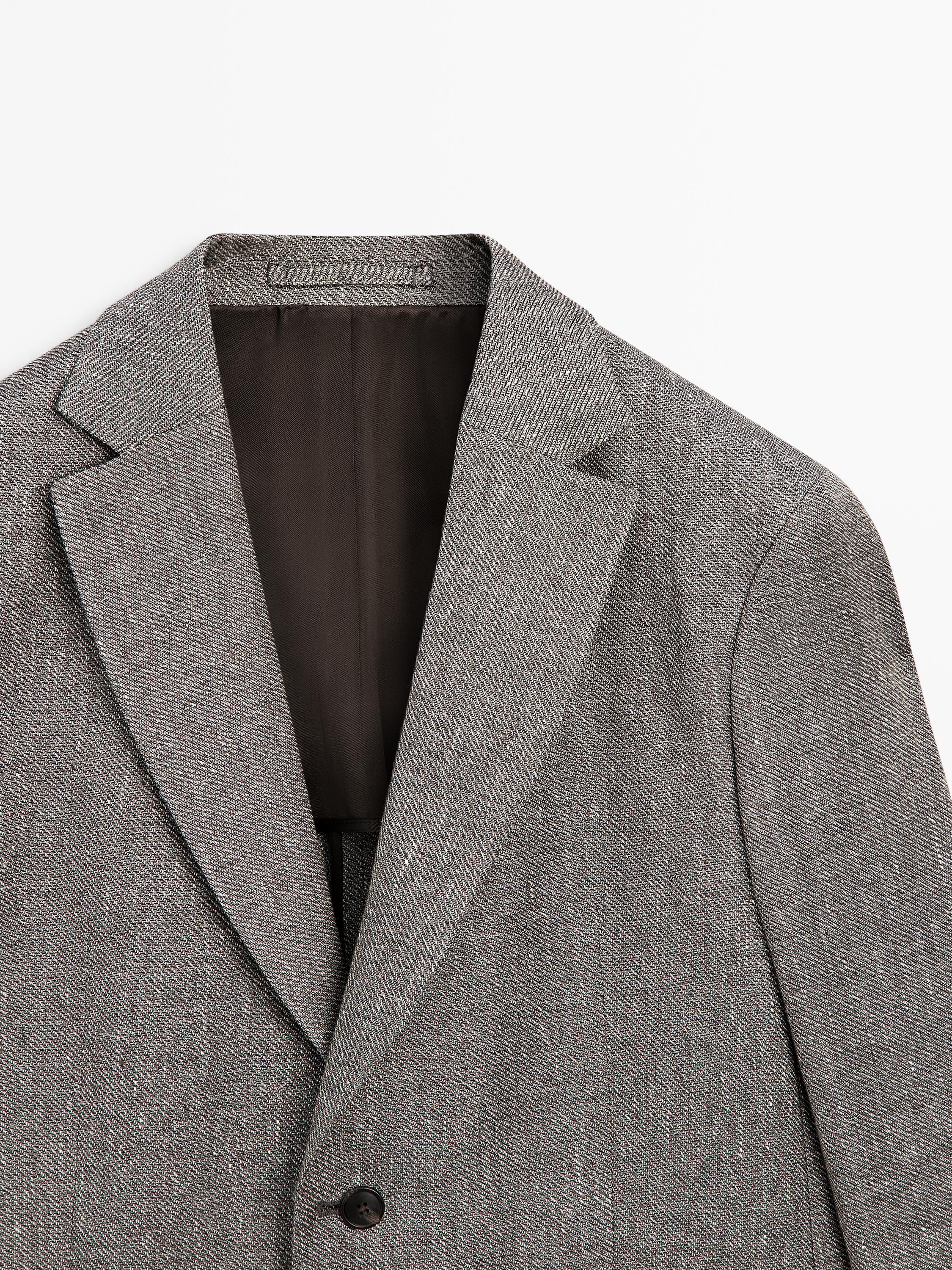 Plano medio da solapa e abotoadura de blazer gris vigoré con forro escuro.