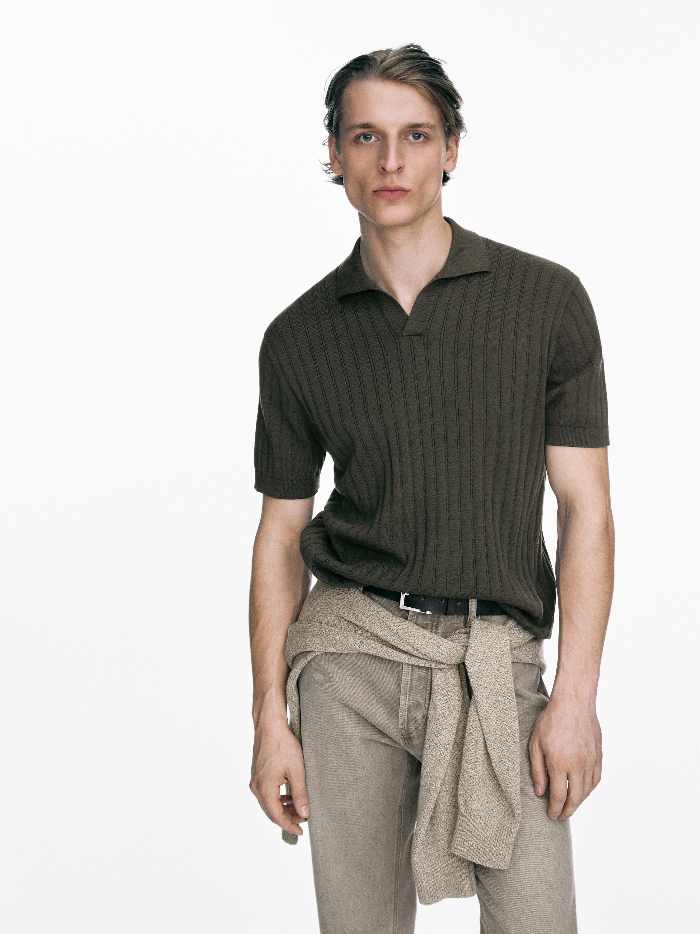 Conjunto de jersey polo caqui oscuro de punto trenzado con pantalones beige y suéter atado a la cintura.
