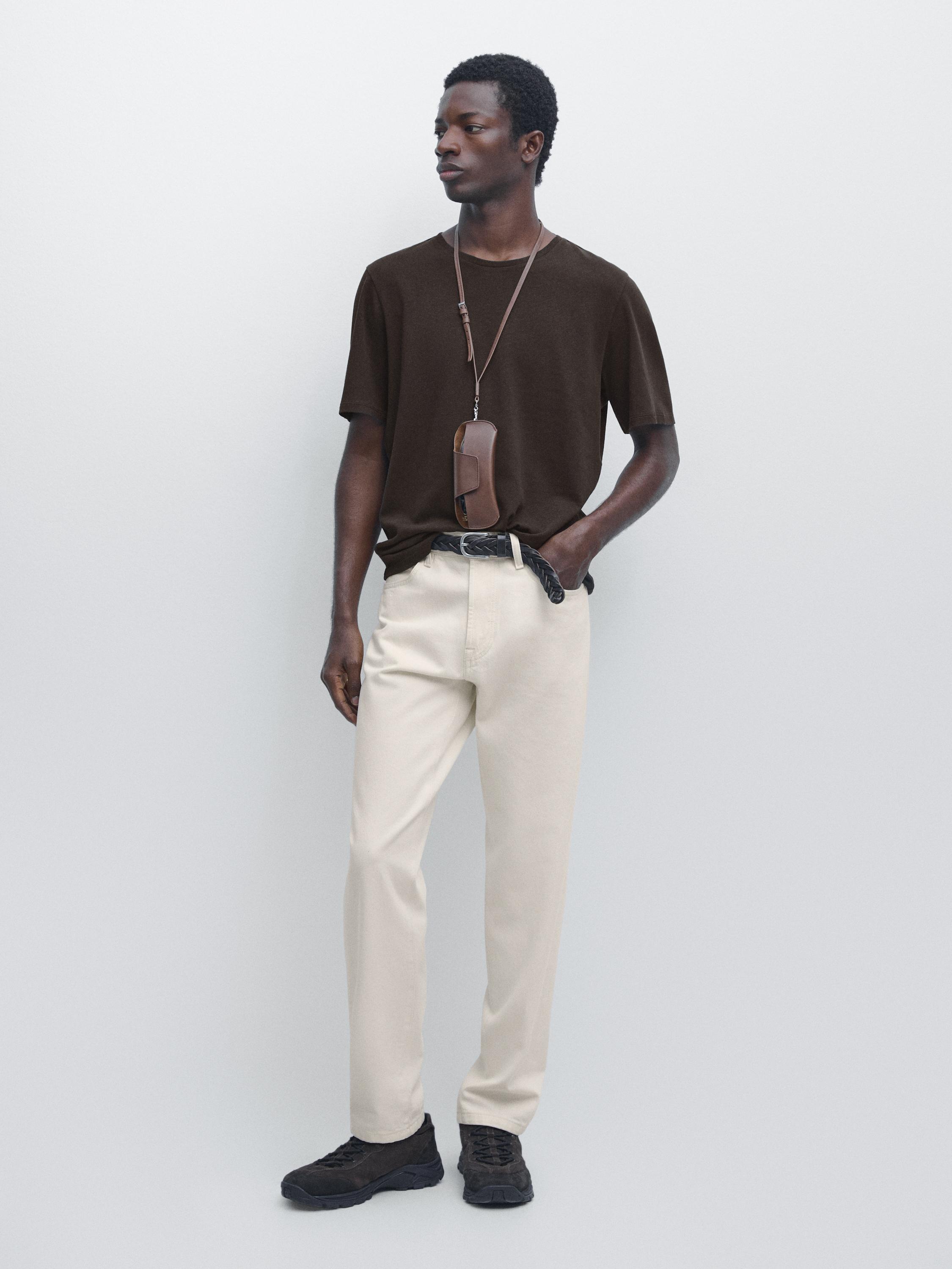 Set of short-sleeved brown T-shirt and beige pants with a black belt and dark shoes.
