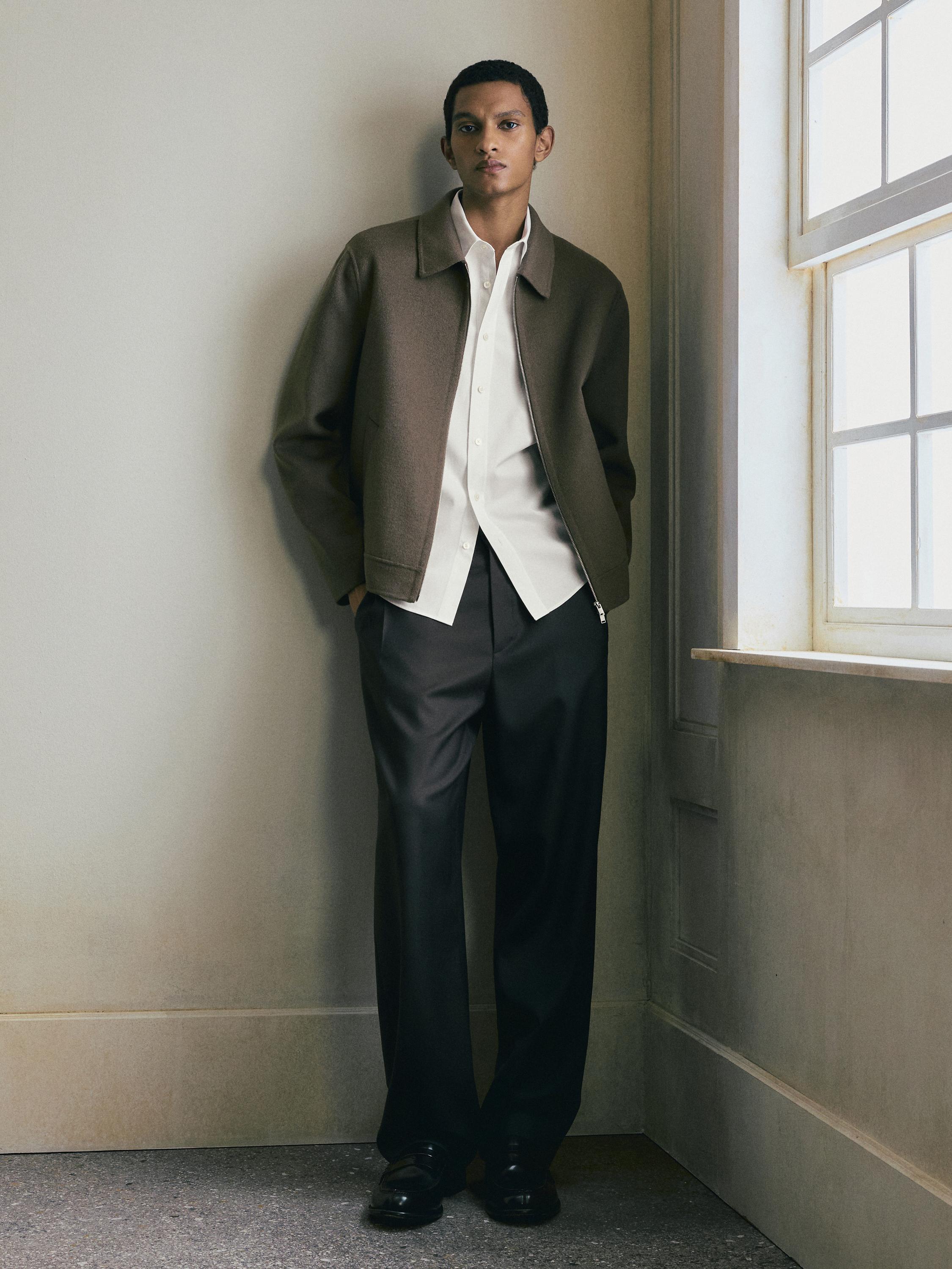 Sæt med brun lynlåsjakke, hvid skjorte og sorte bukser med lige ben.