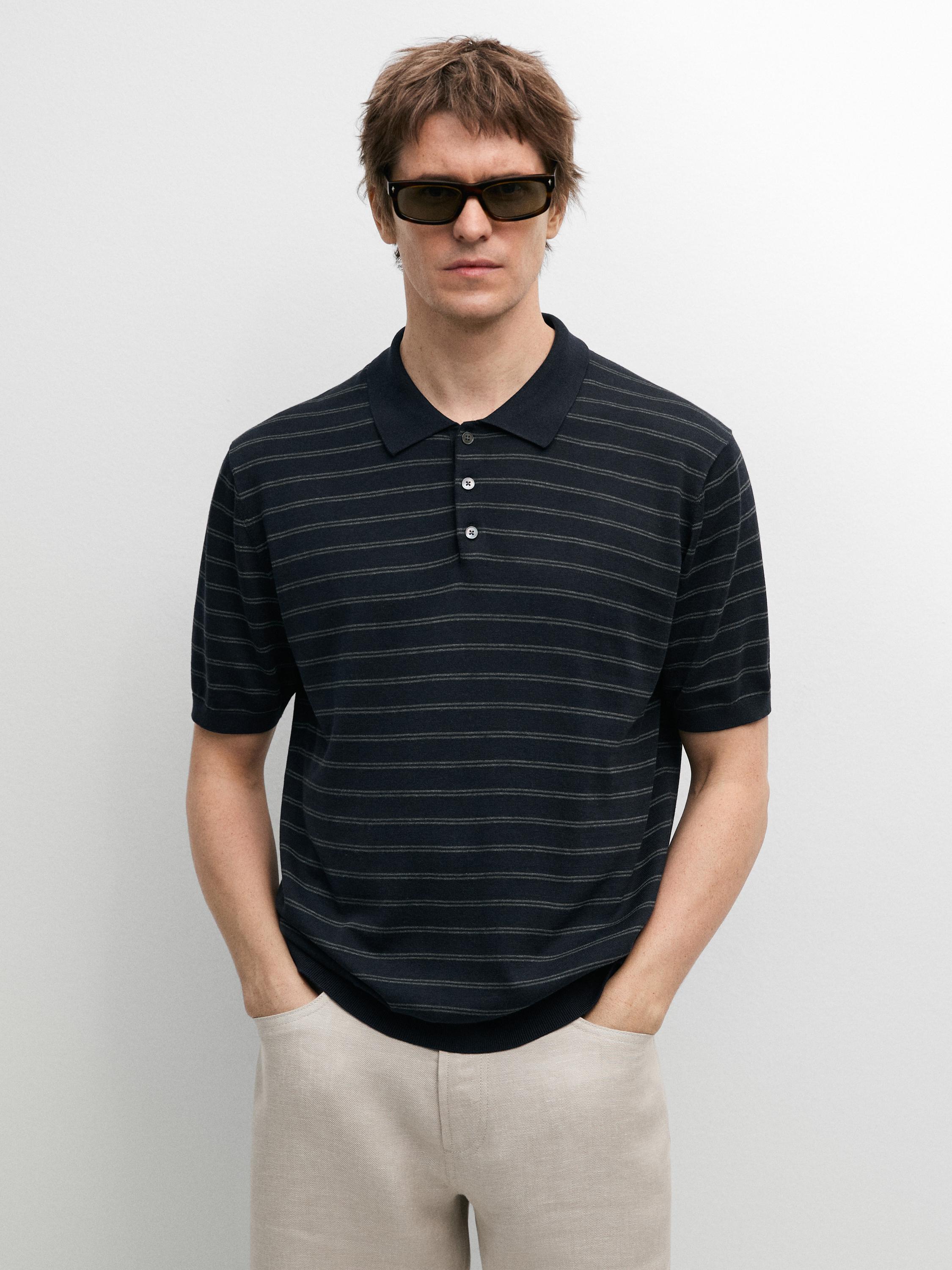 Ensemble polo bleu marine à rayures et boutons sur le devant, associé à un pantalon beige.