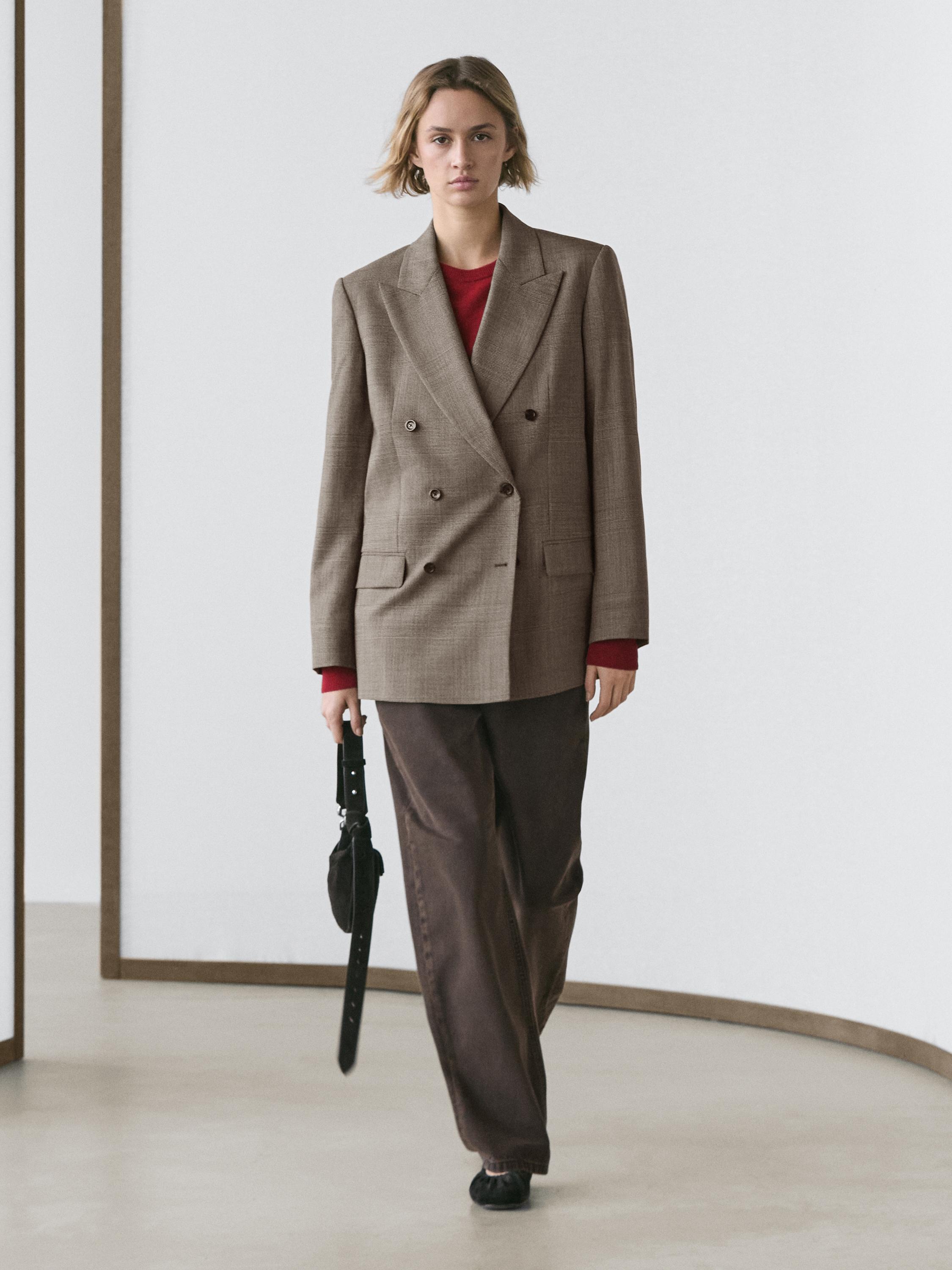 Double-breasted beige blazer set with buttons and flap pockets, brown pants, and a red t-shirt visible at the neck.