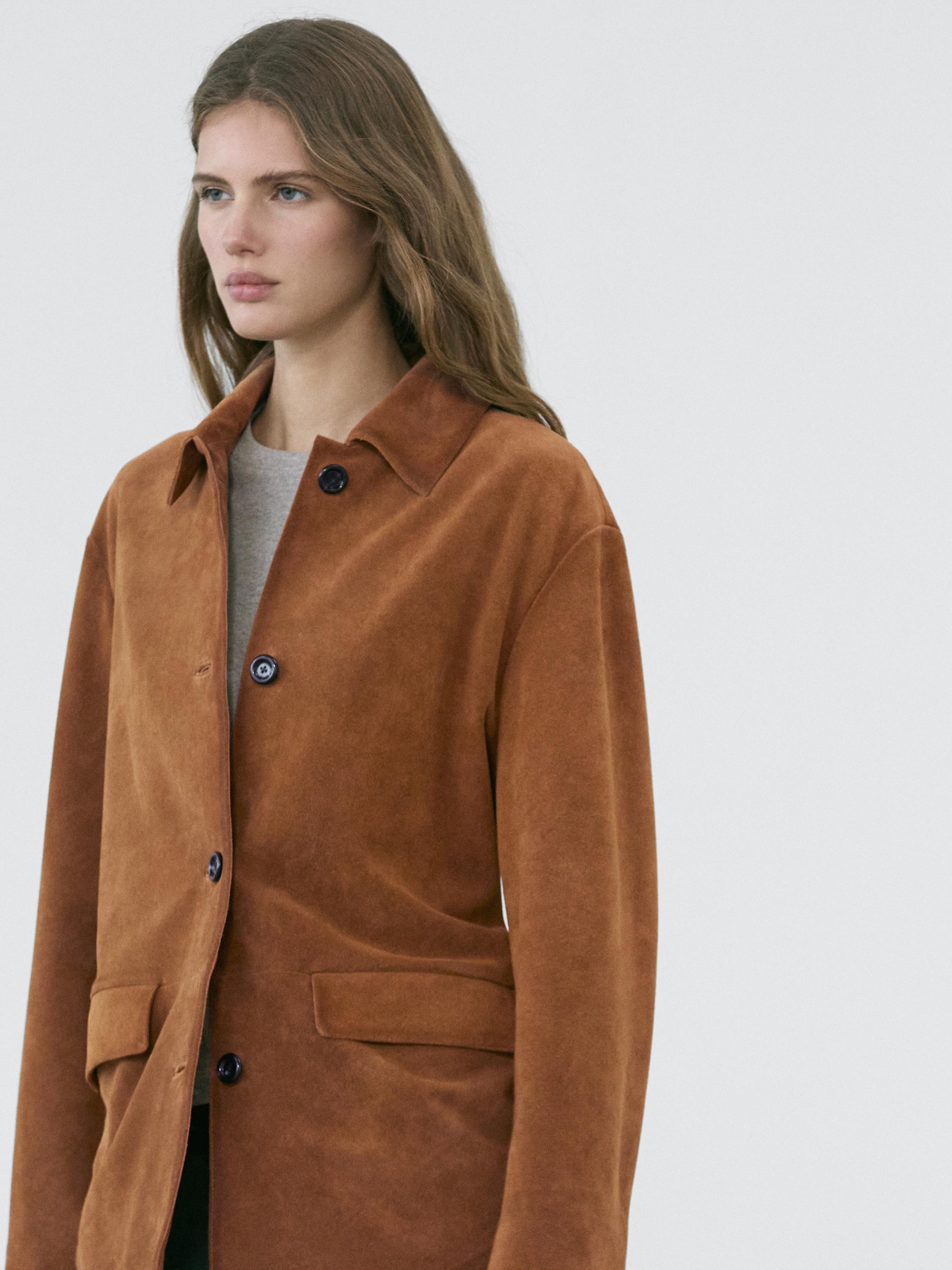 Plano medio de chaqueta camel con botones oscuros y bolsillos frontales con solapa.