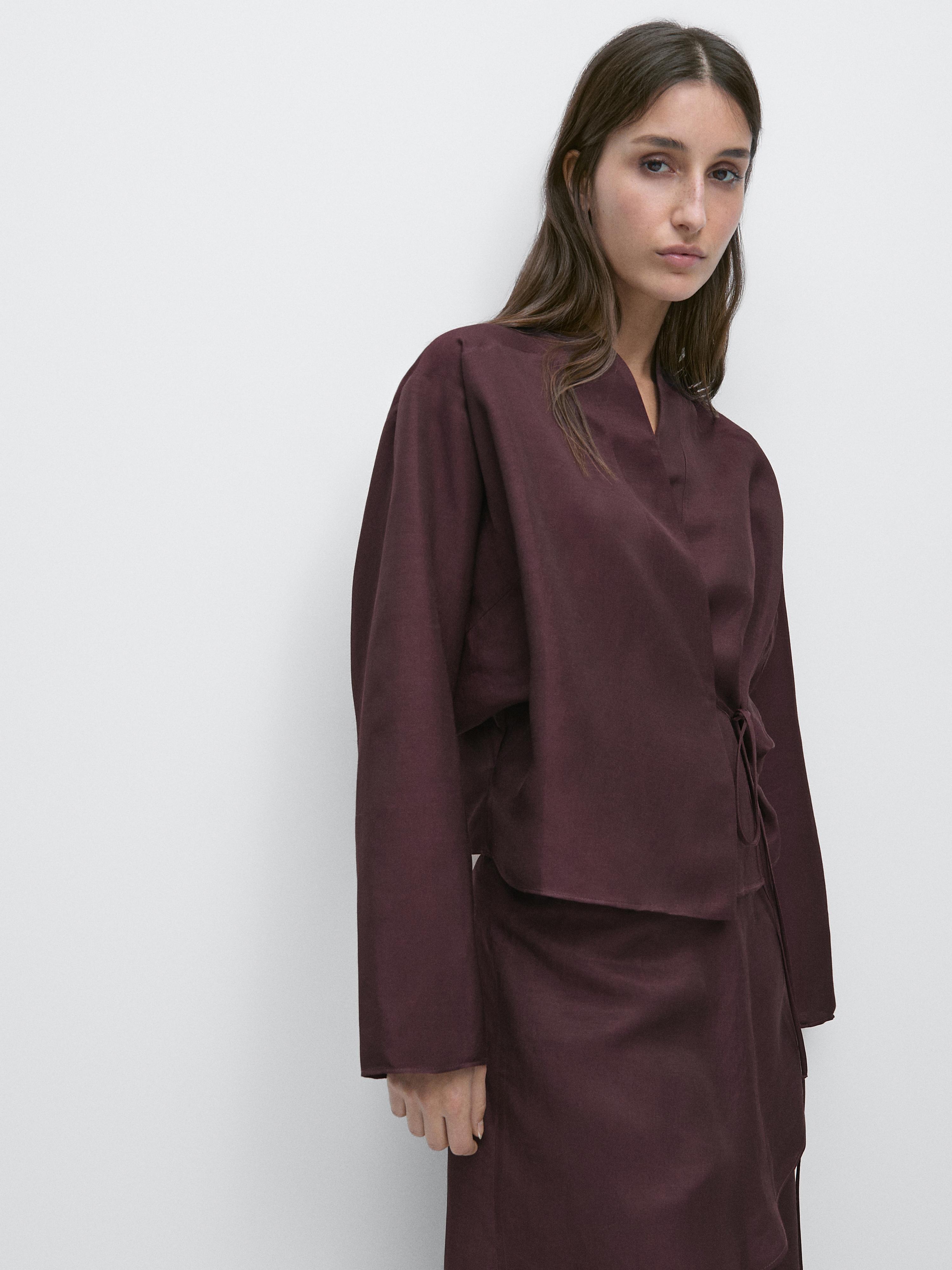 لقطة متوسطة لقميص بلون الباذنجان بياقة على شكل حرف V وإغلاق جانبي قابل للتعديل.