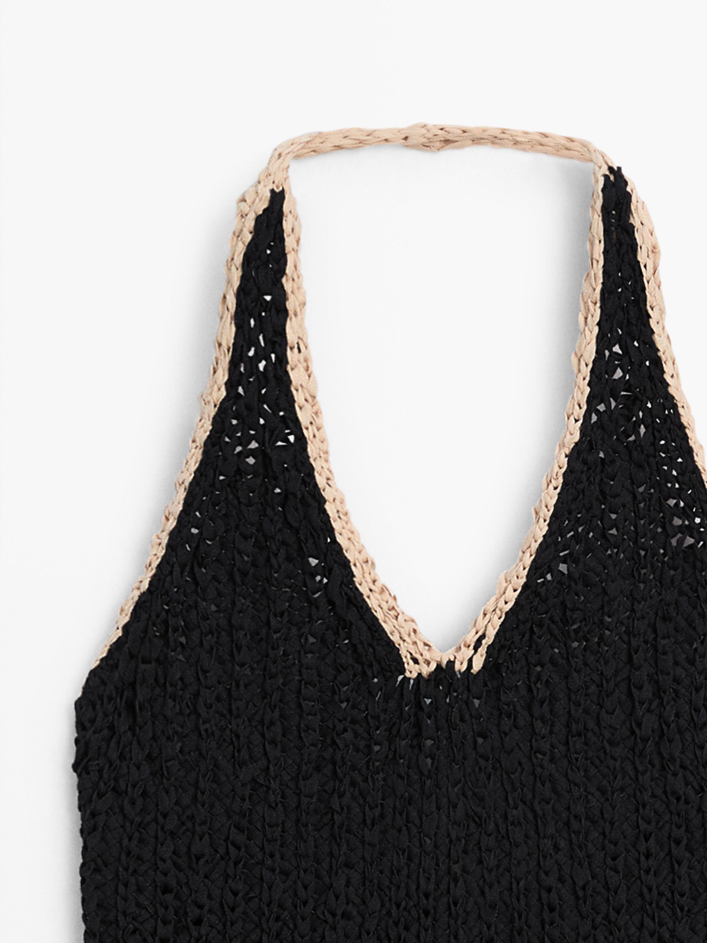 "Eskote-xehetasuna tirante beixak dituen top beltz trikotatu batean."