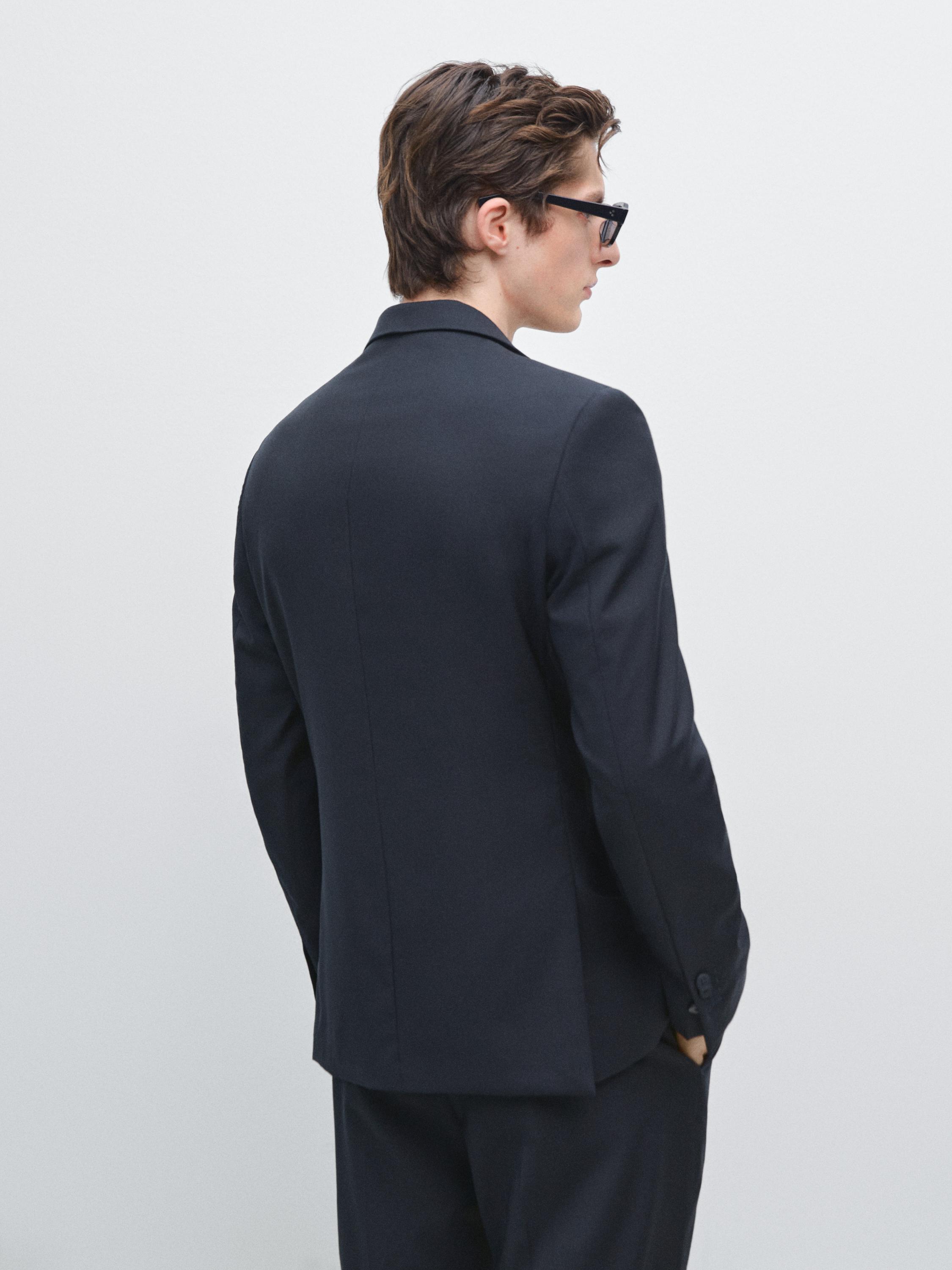 Achterkant van een marineblauwe blazer met klassieke revers en zijzakken.