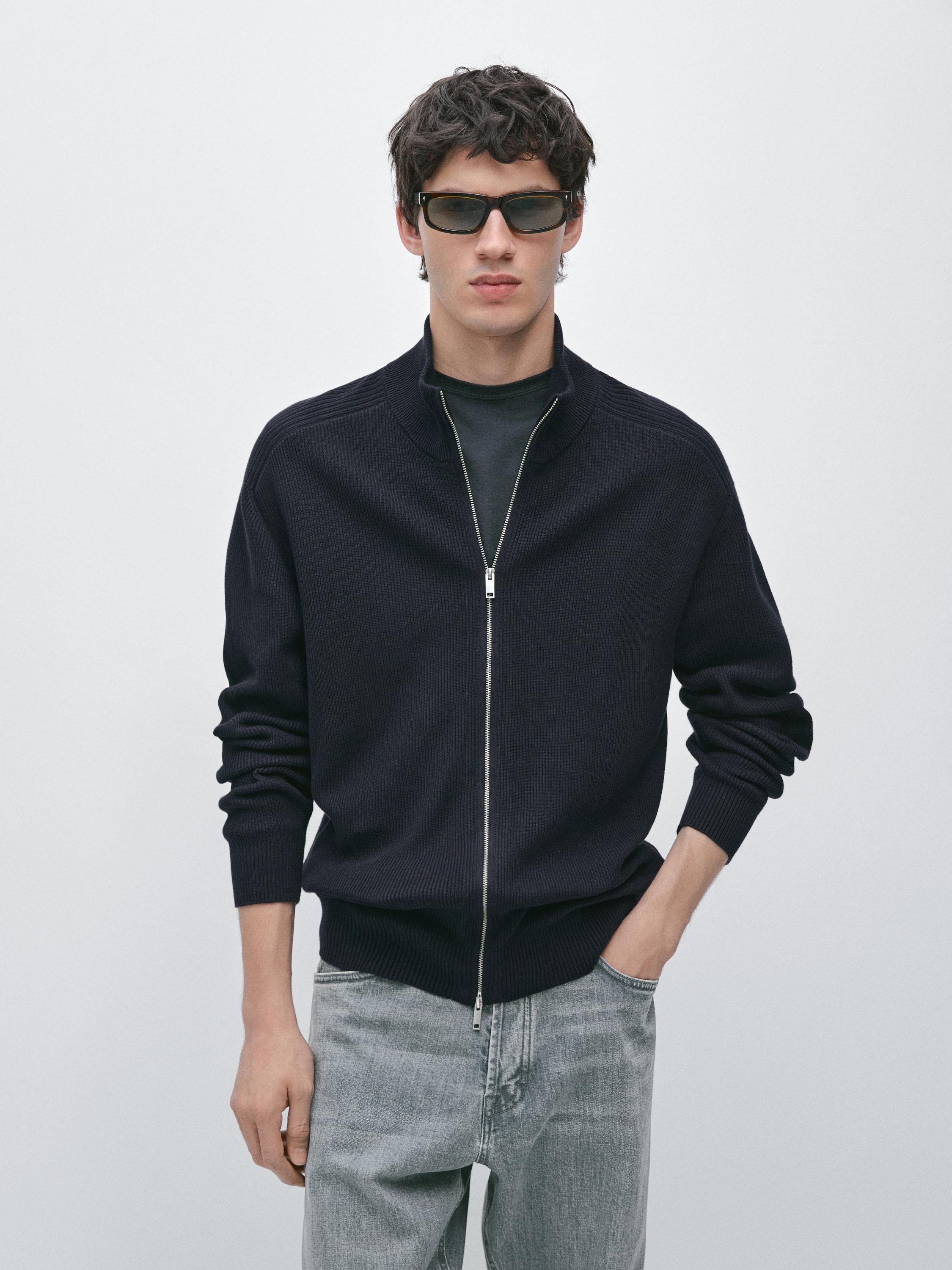 Conjunto de cárdigan azul marino con cremallera frontal y jeans grises.