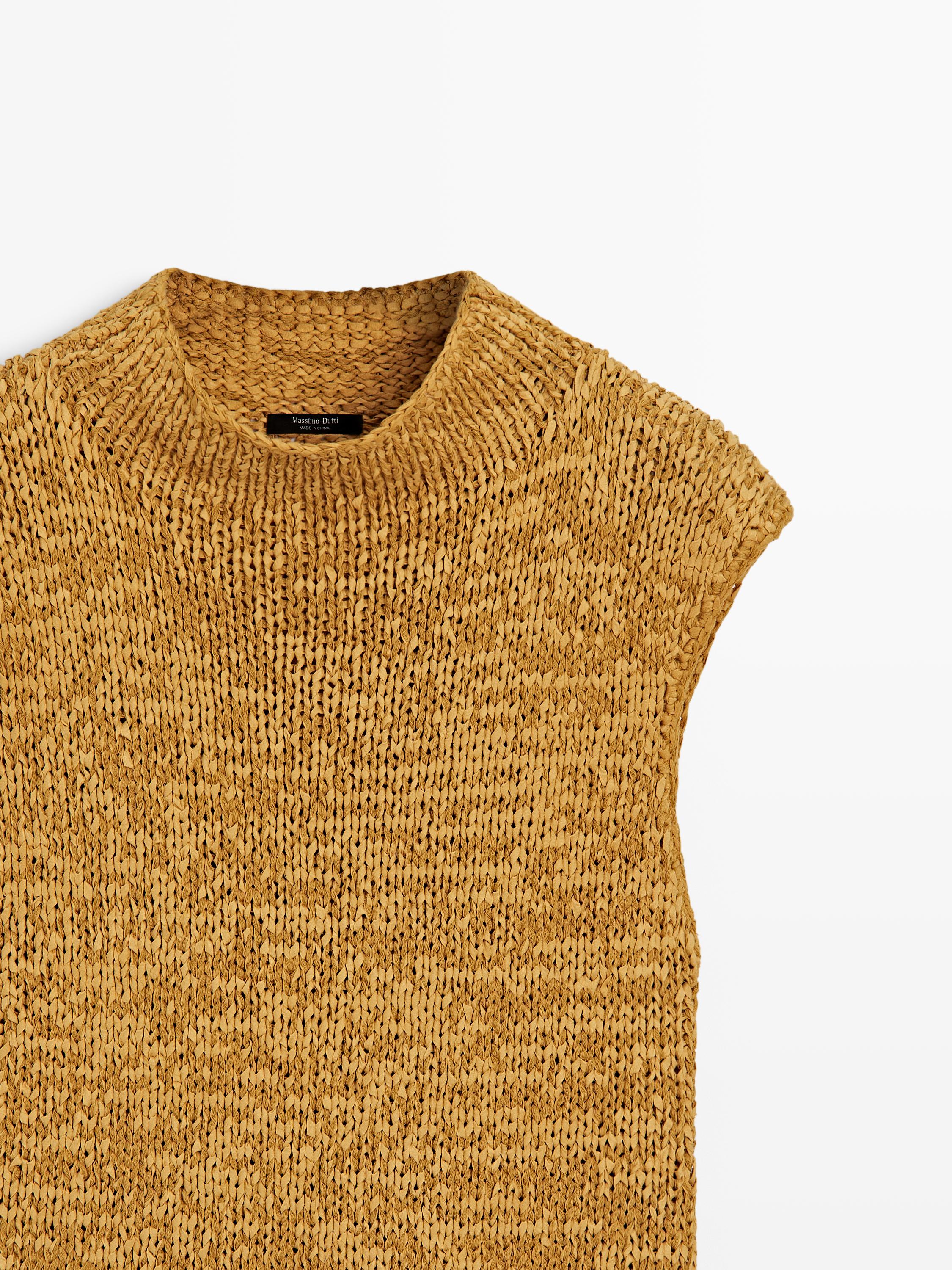 "Plano medio de top de punto color curry con cuello redondo alto y sisa, detalle de punto jaspeado."