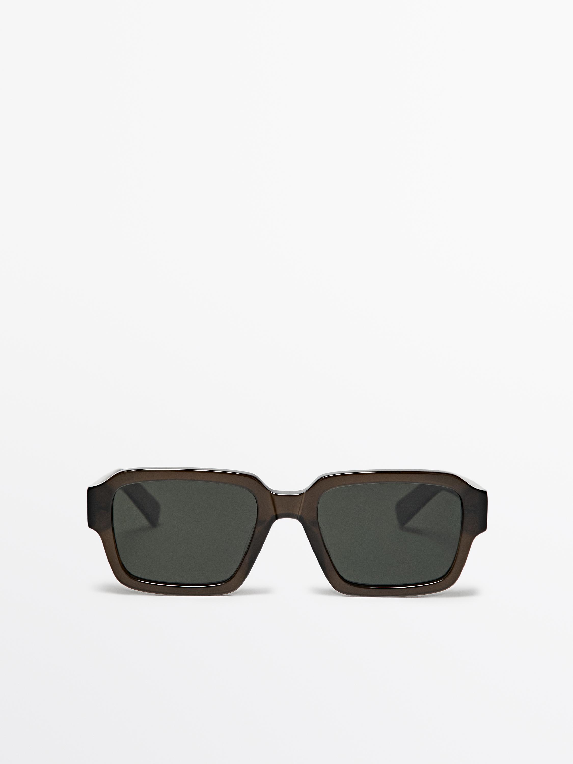 Vista frontal d'ulleres de sol rectangulars de color verd amb muntura gruixuda i lents fosques.