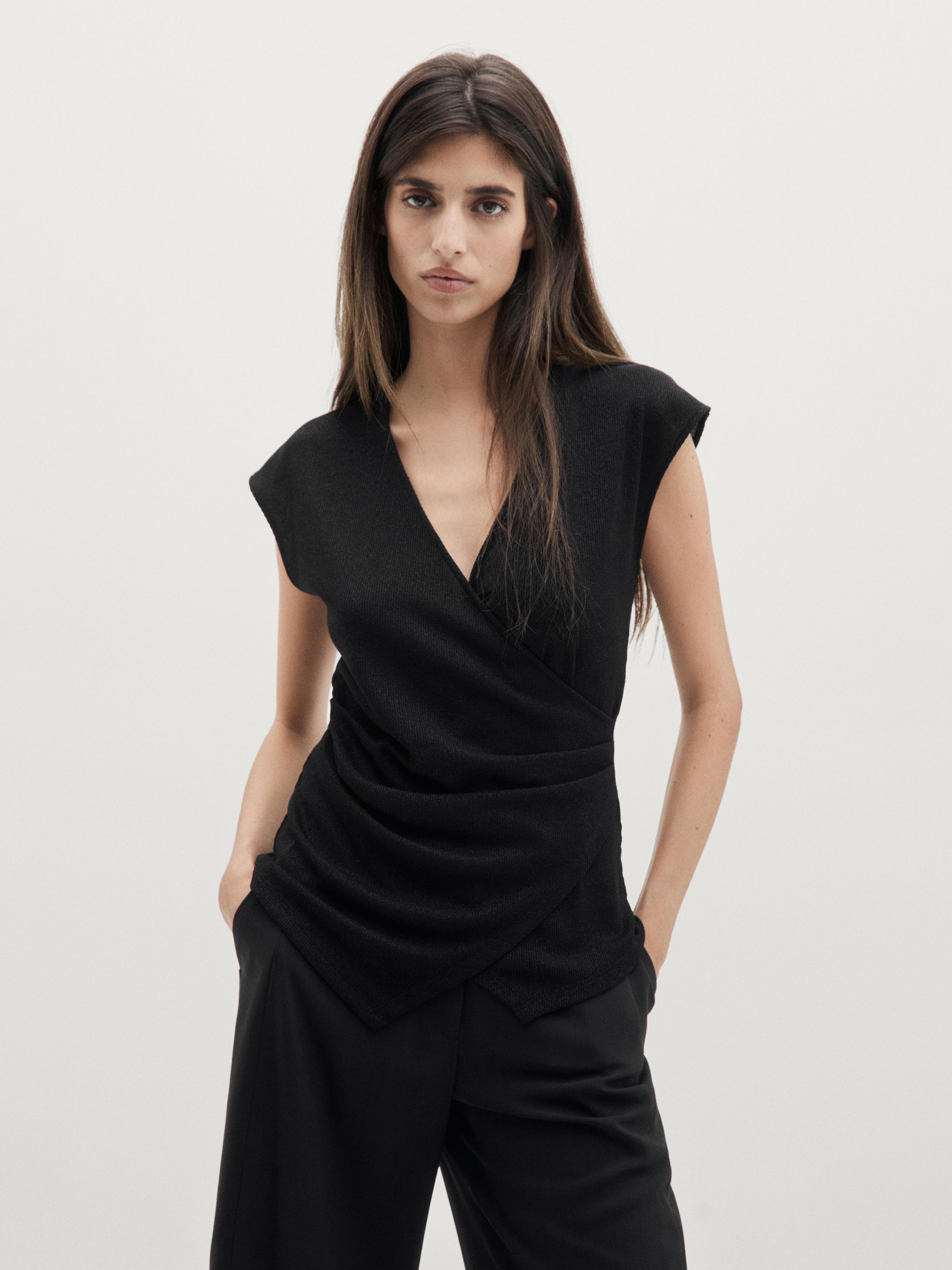 Conjunto de top negro con escote cruzado y pantalones negros.