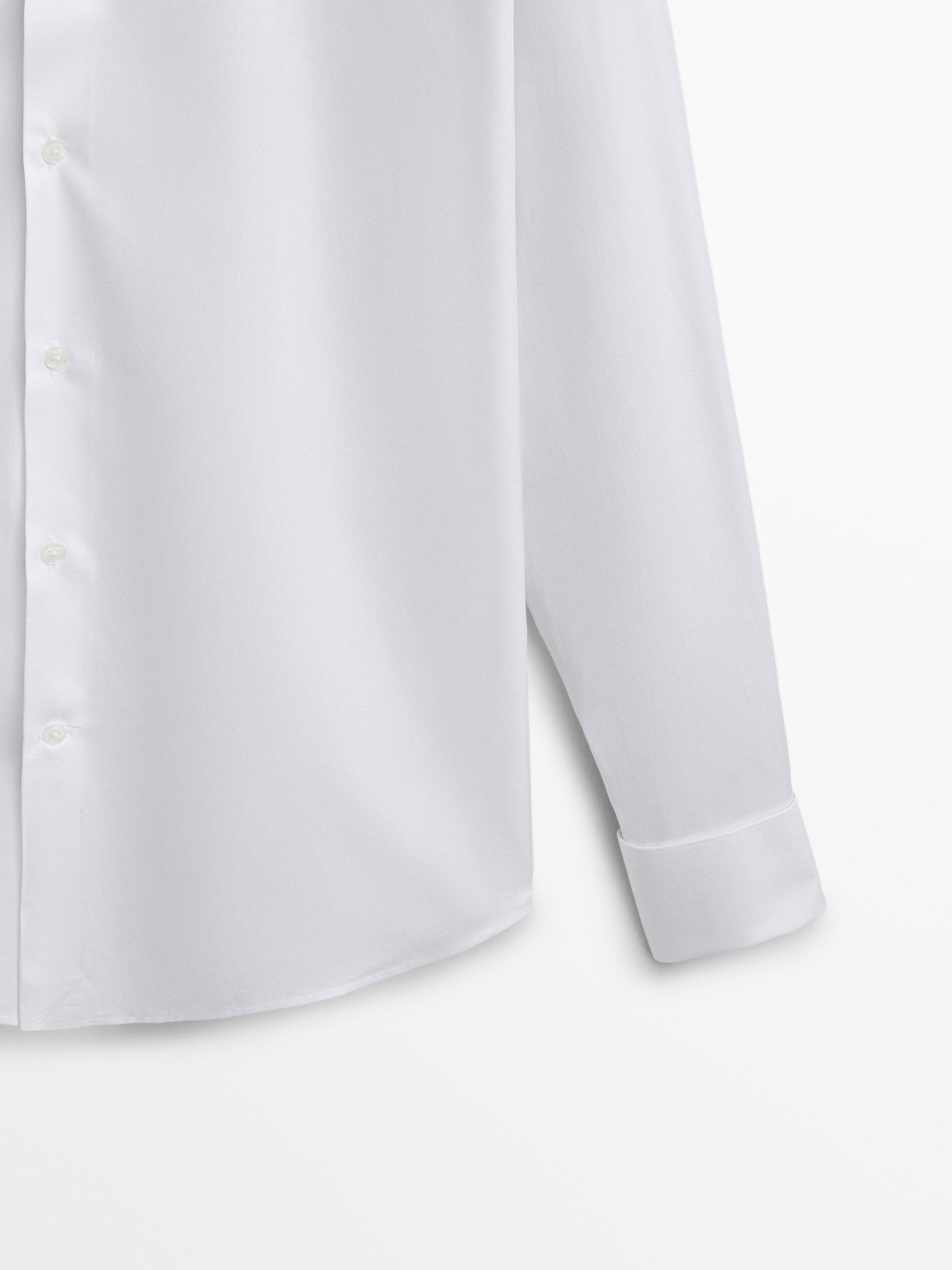 Détail de la manche et de la patte de boutonnage latérale d'une chemise blanche
