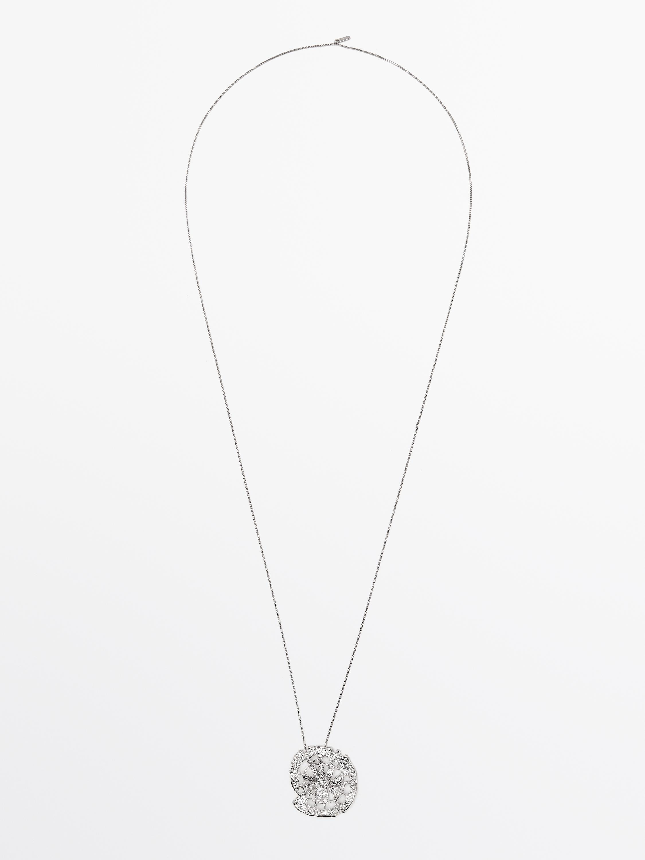 Длинное серебряное колье с круглым текстурированным кулоном.