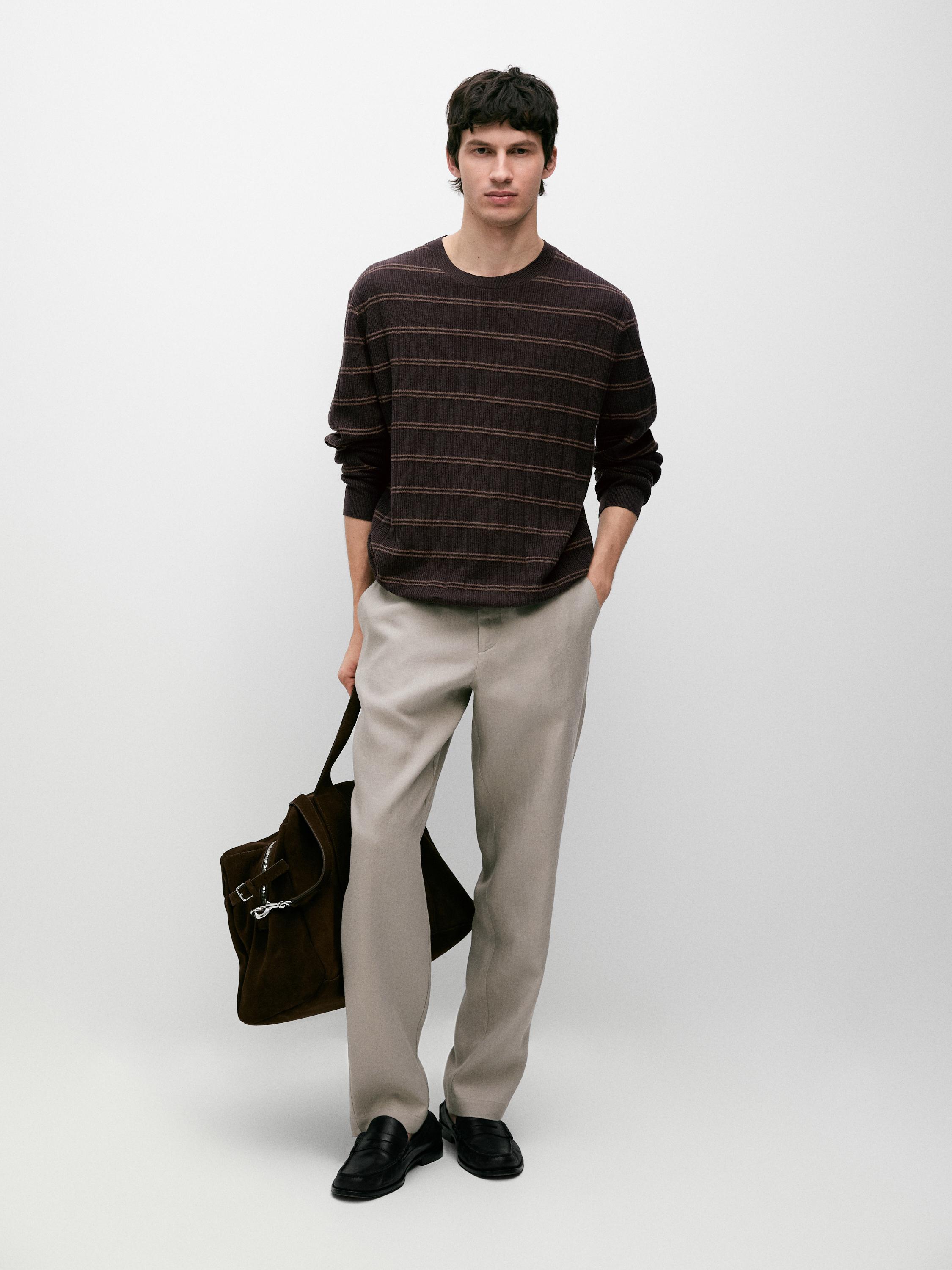 Brown striped sweater and beige tapered-fit pants with side pockets.