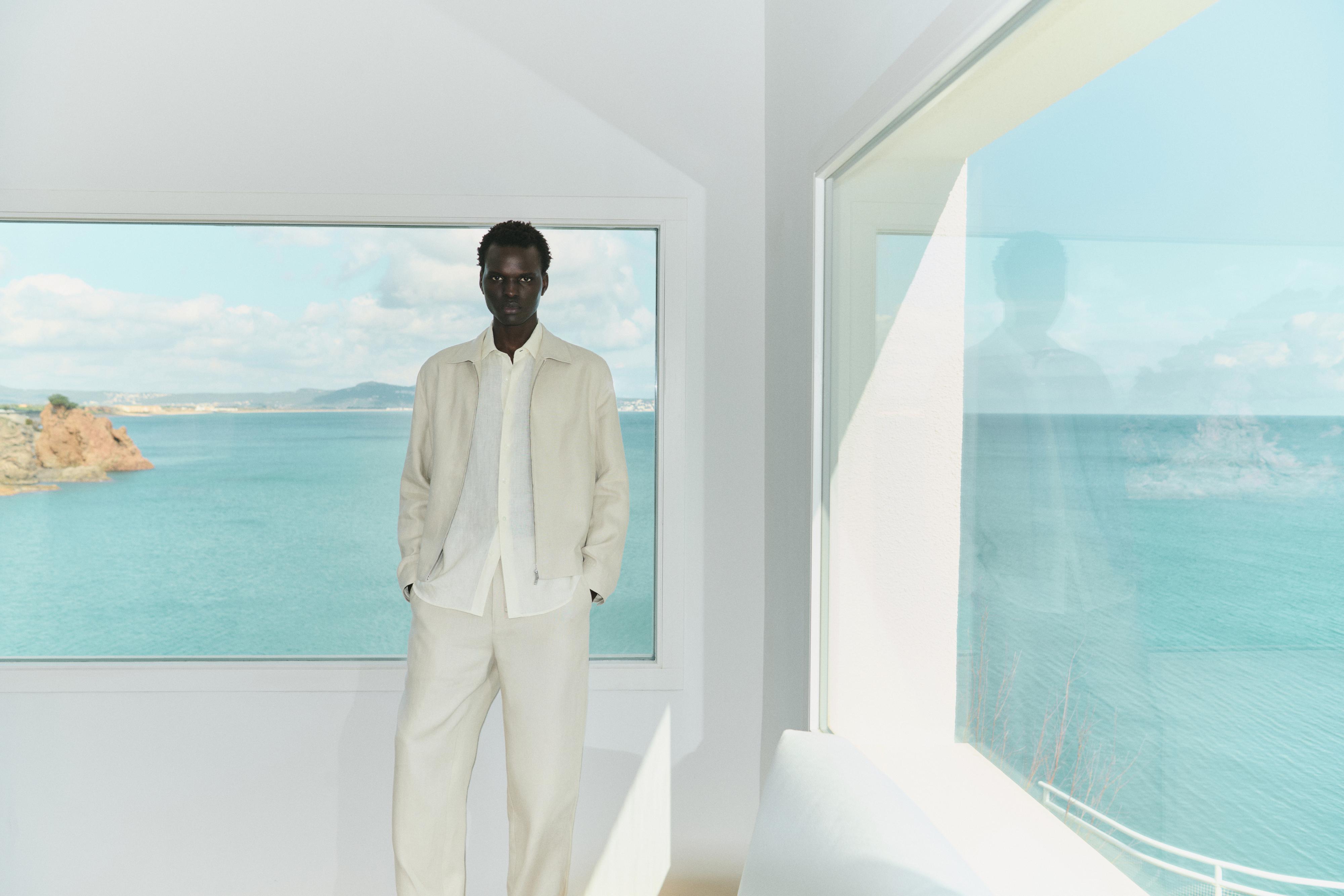 Conjunto de chaqueta y pantalón beige con camisa blanca.