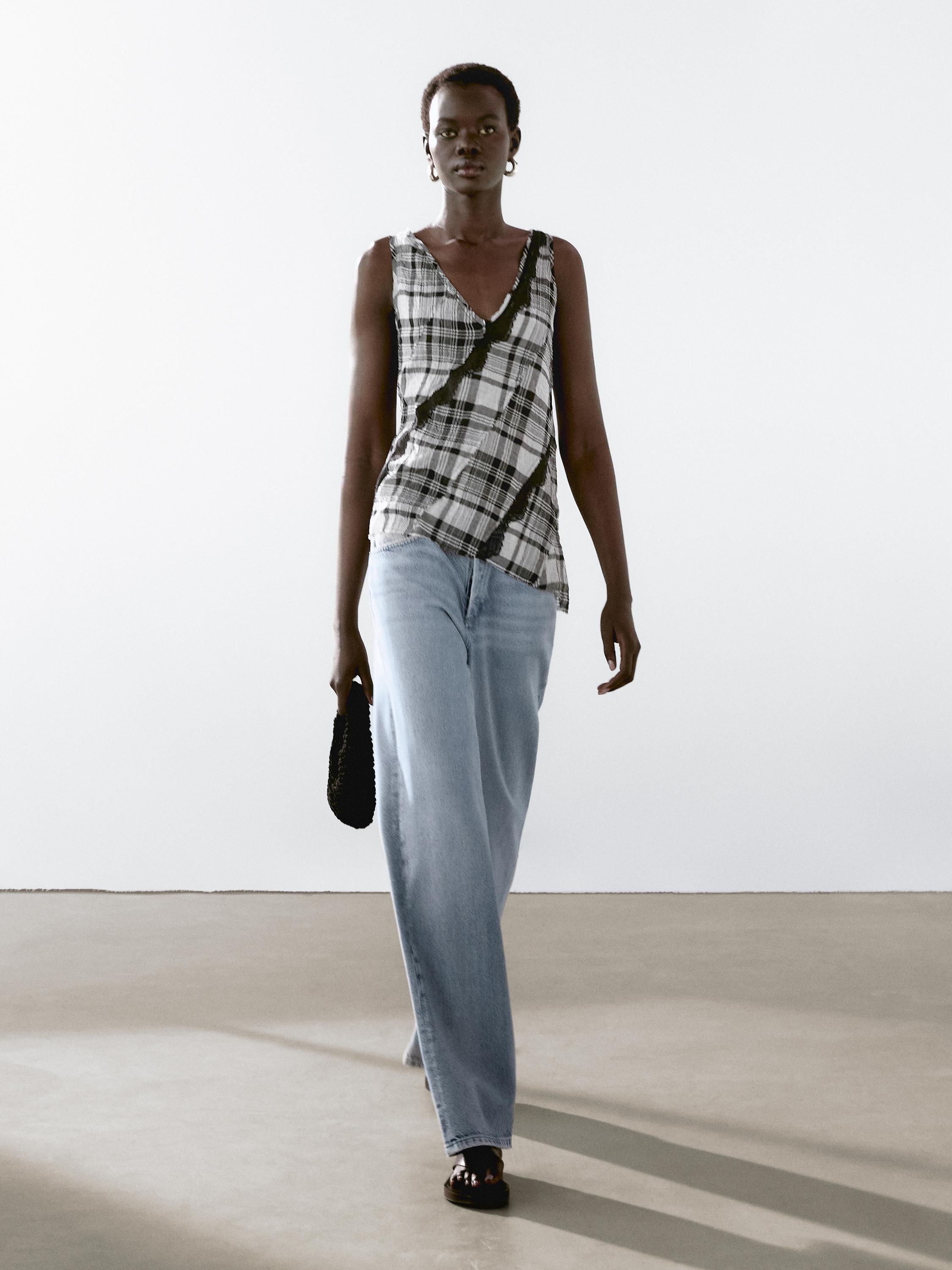 Ensemble composé d'un haut à carreaux et d'un jean bleu à jambes larges.