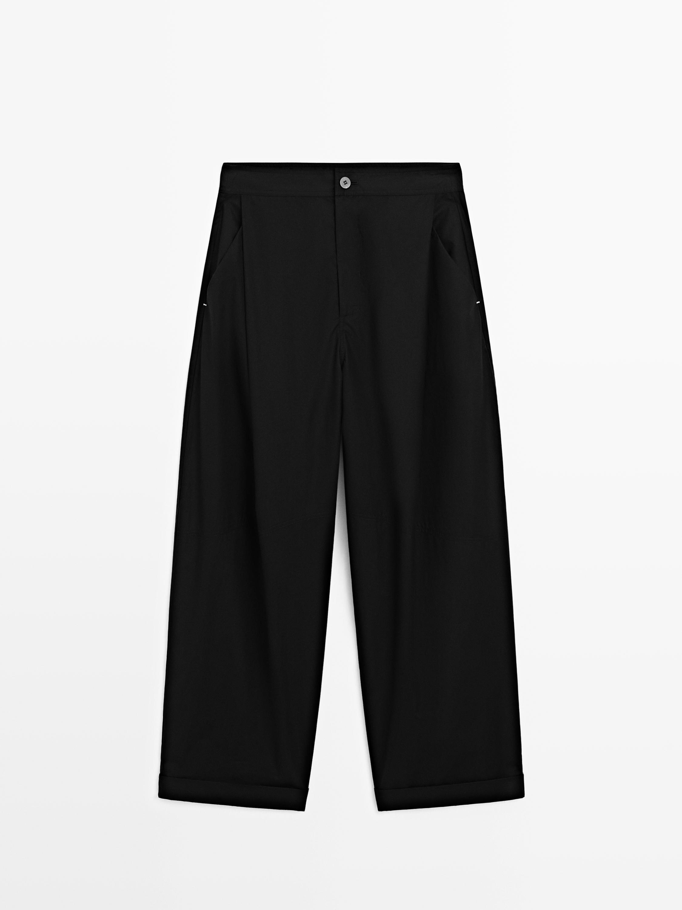Front view of black barrel fit pants with hem and side pockets.