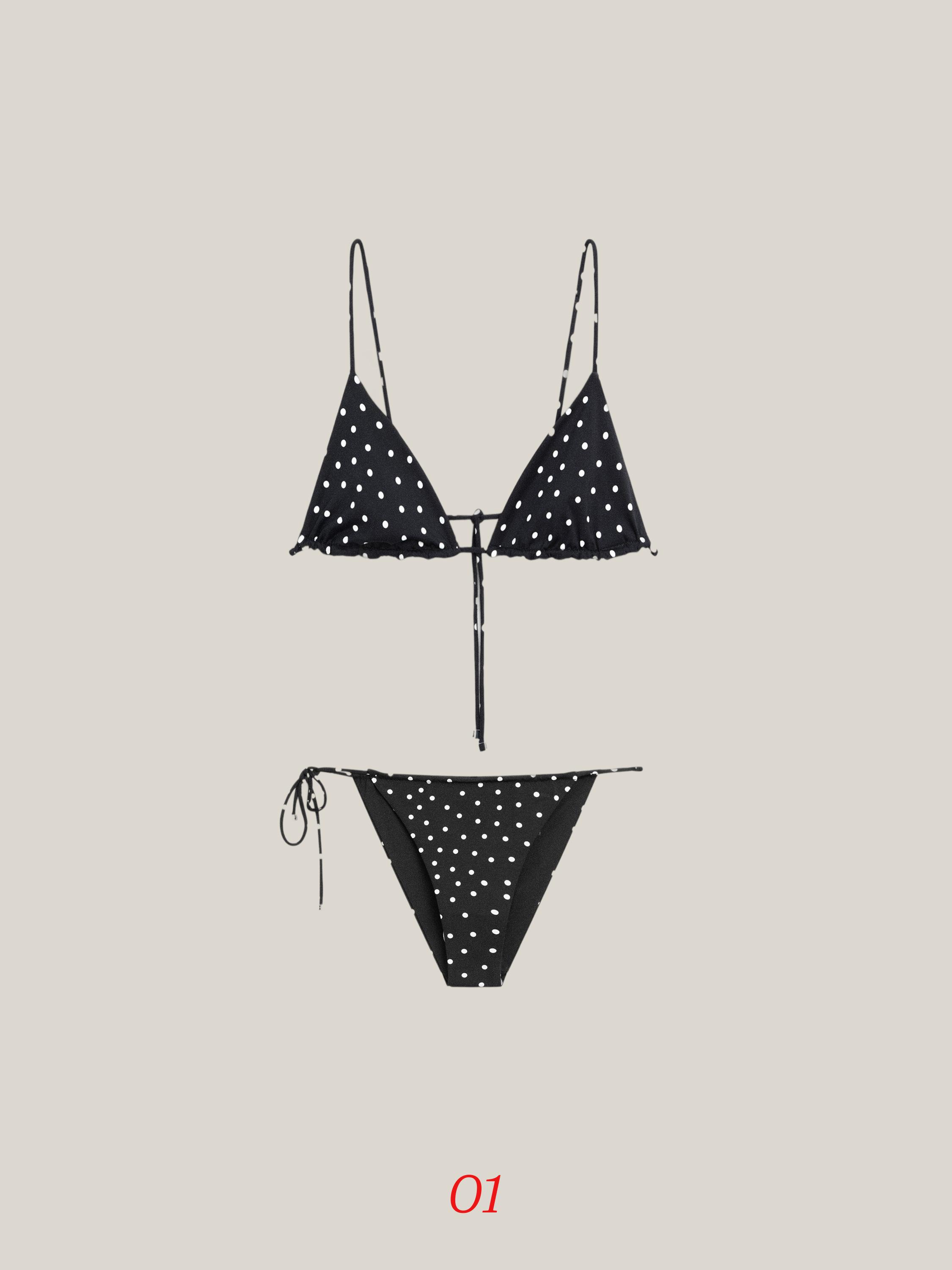 Vista frontal de bikini negro con estampado de lunares blancos, tirantes finos y lazos ajustables en la parte inferior.