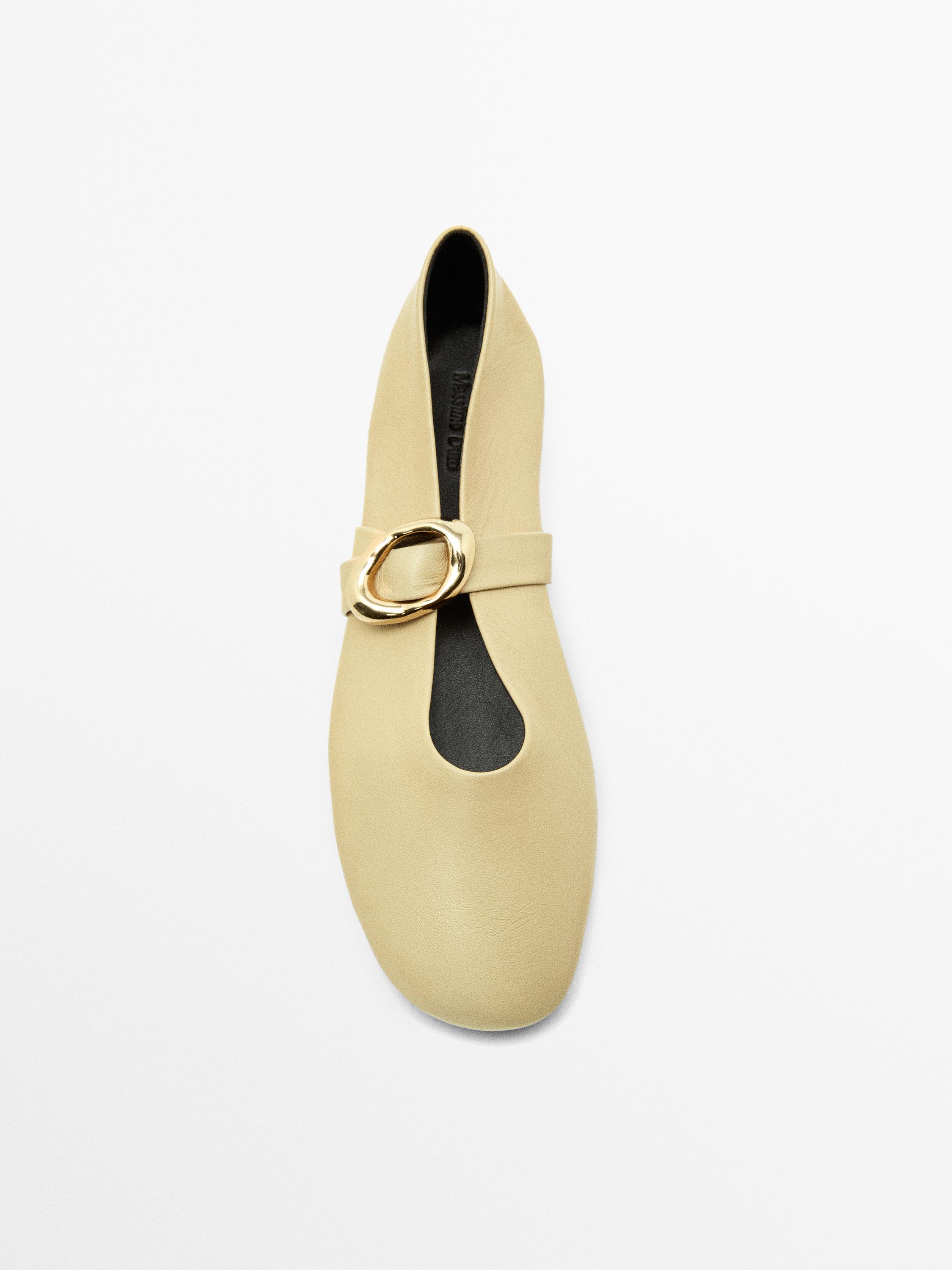 Vista superior de bailarina crudo con hebilla dorada en el empeine.