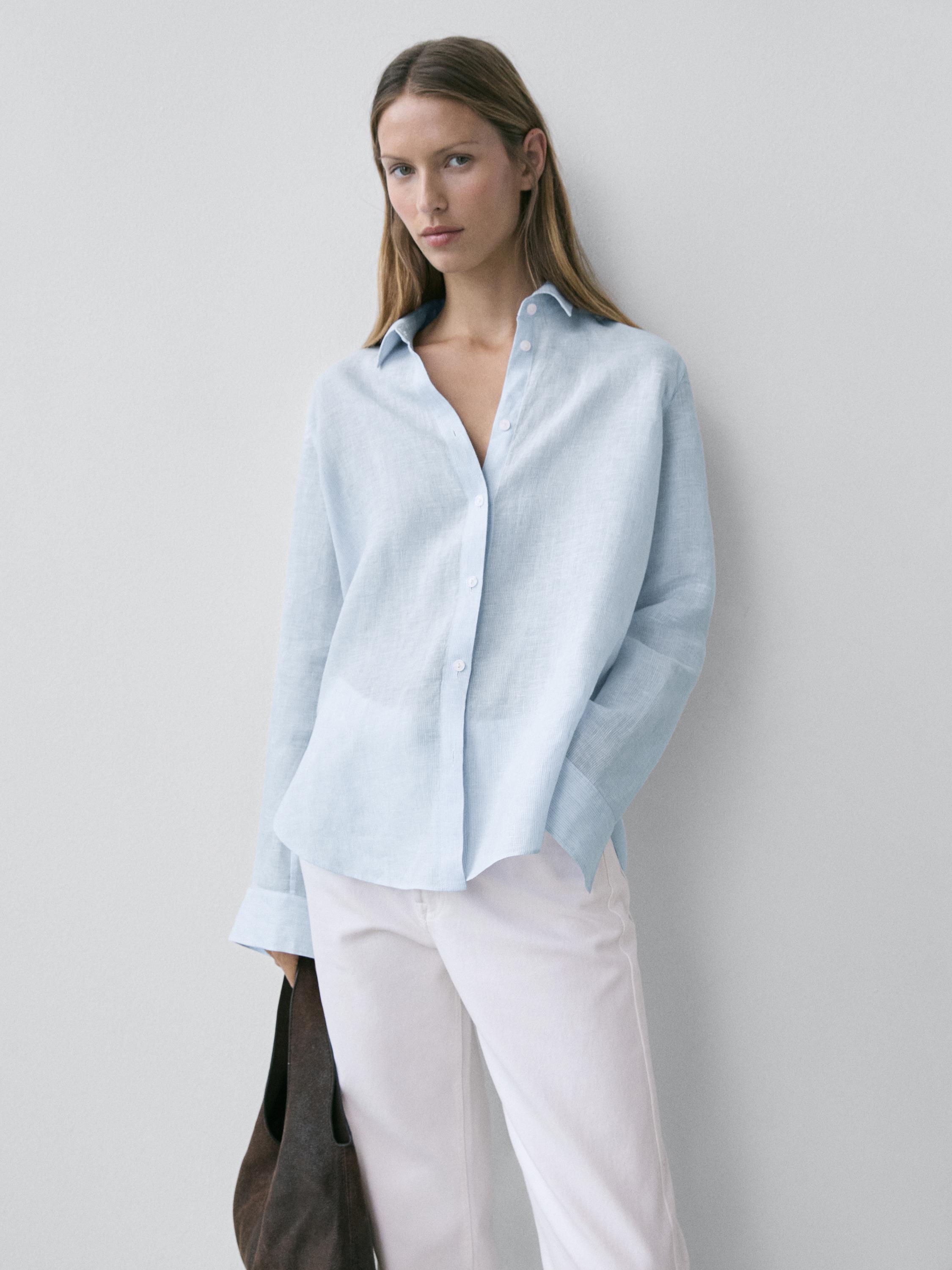 Conjunto de camisa azul claro suelta con botones y cuello clásico, combinado con pantalones blancos.